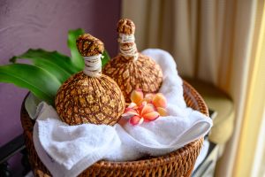 Thai massage with herbal hot compress ball on wooden tray